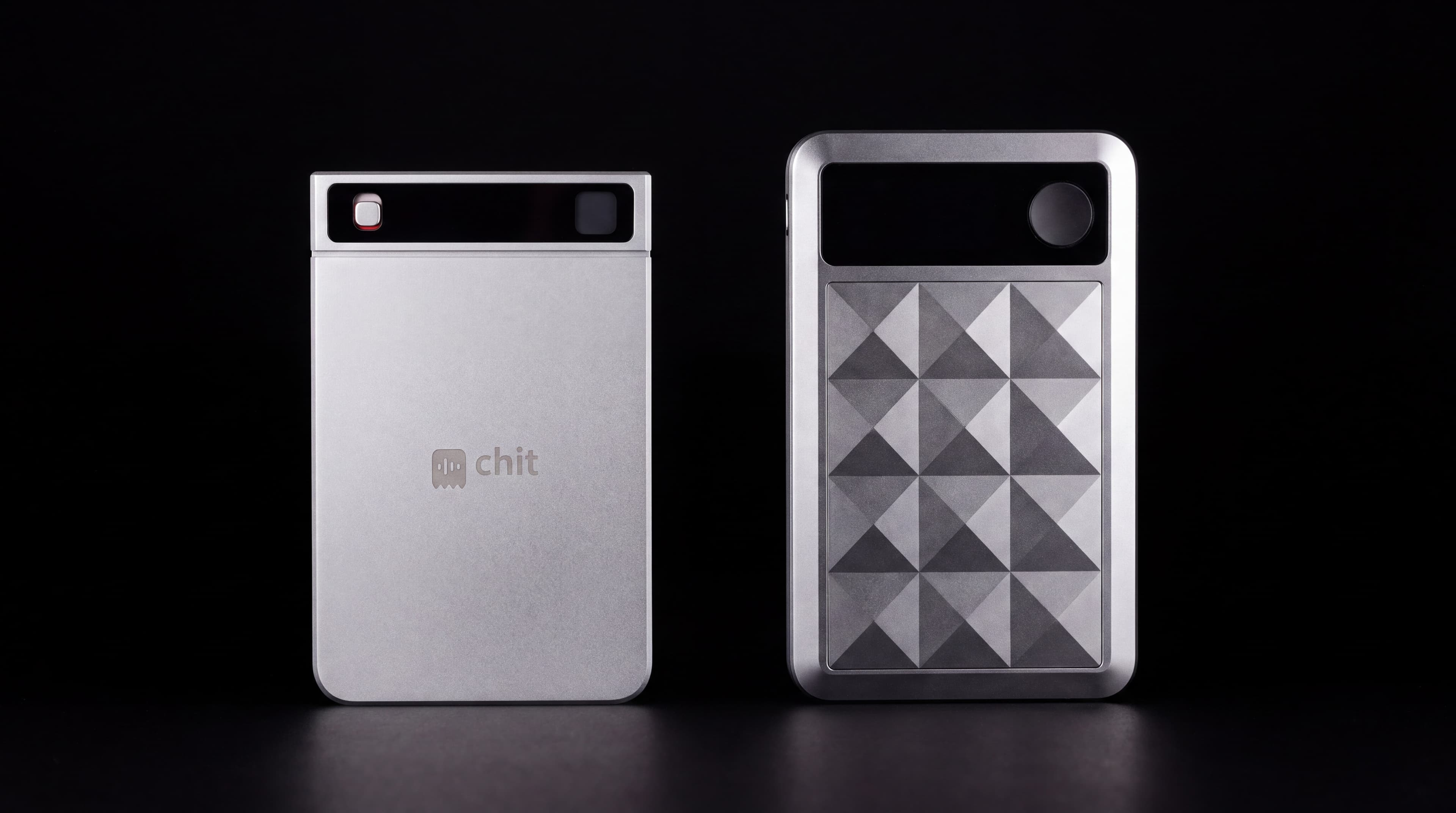 chit one and chit one Pro side by side in darkness — the Pro a little wider, taller and visibly thicker.